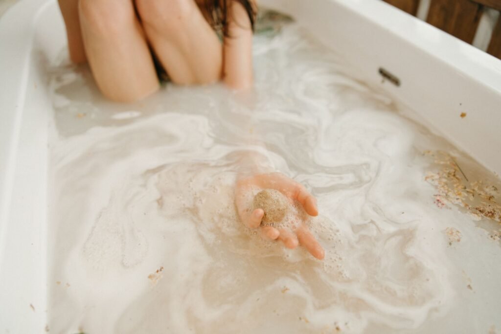 A dissolving bath bomb in a warm bath held in an open hand